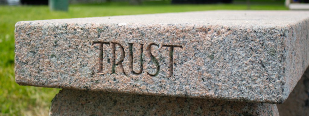 the word trust is carved in a stone bench
