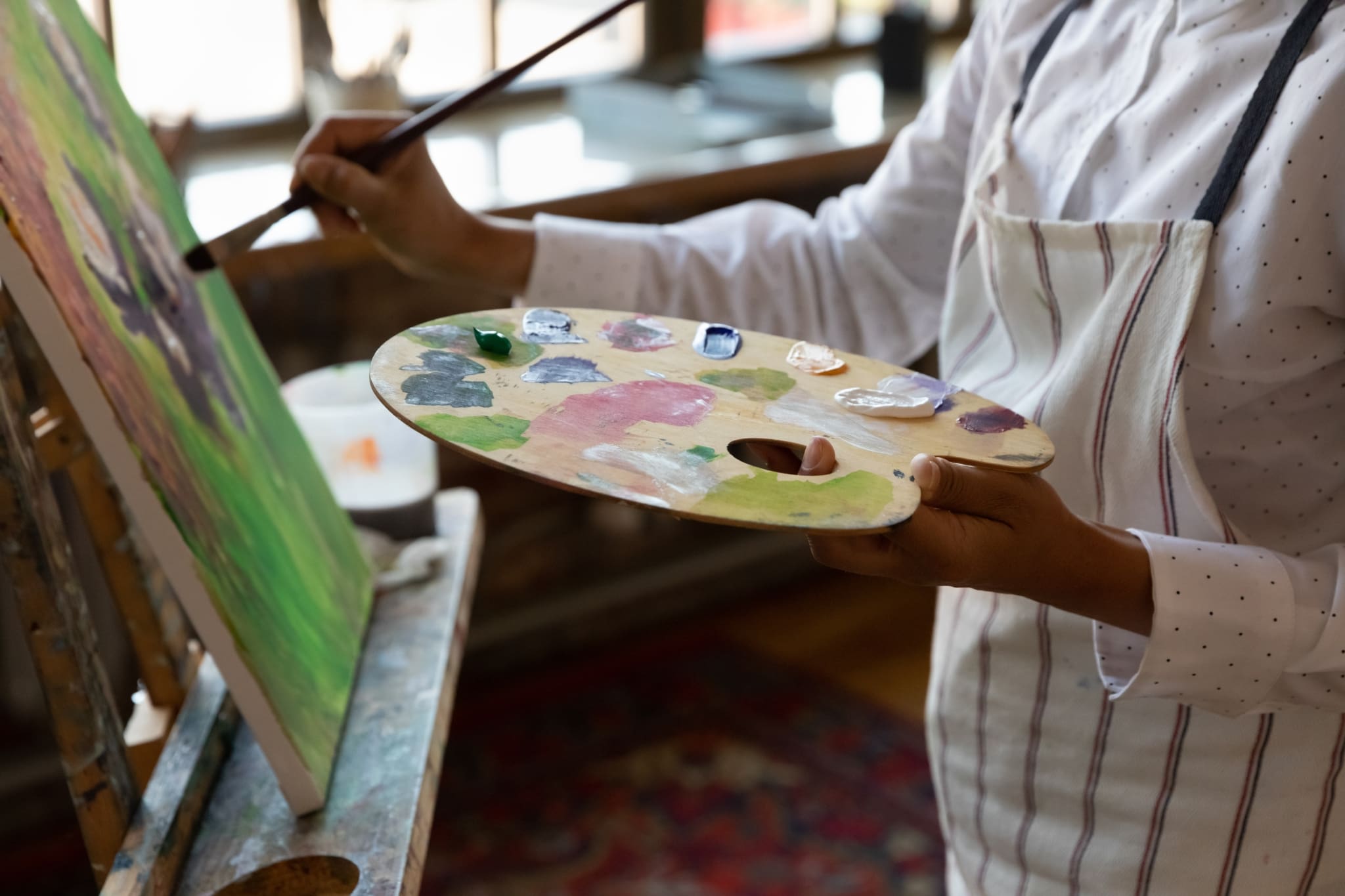 An artist holds a palette and paints a picture.