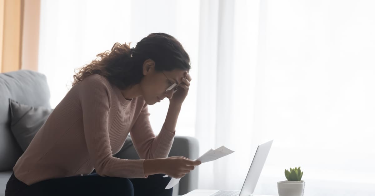 A young woman looks at her bills.