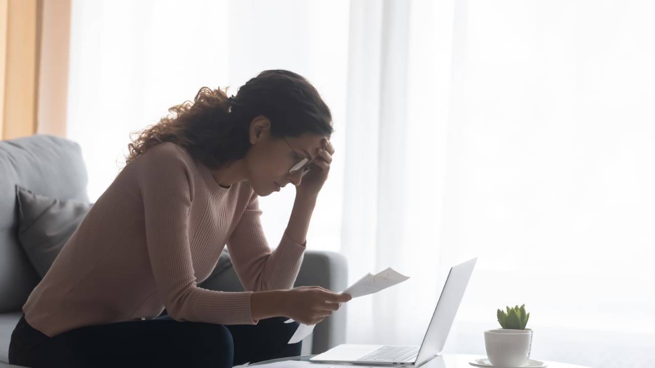 A young woman looks at her bills.