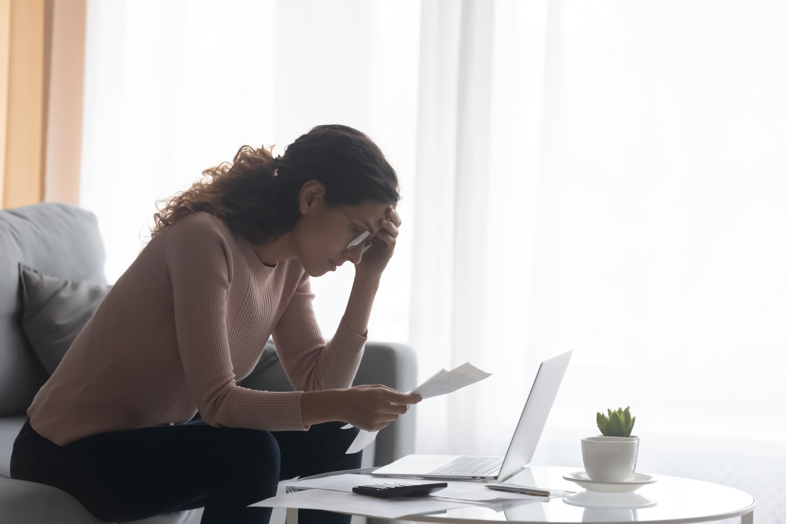 A young woman looks at her bills.
