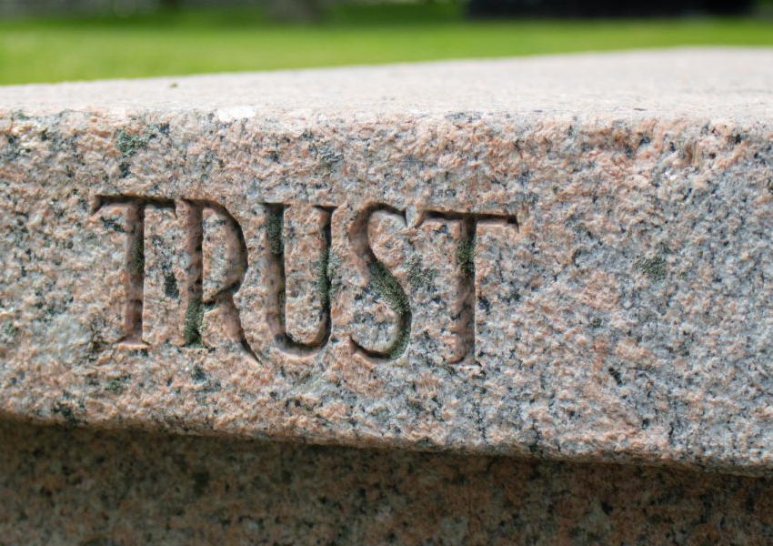 the word trust is carved in a stone bench